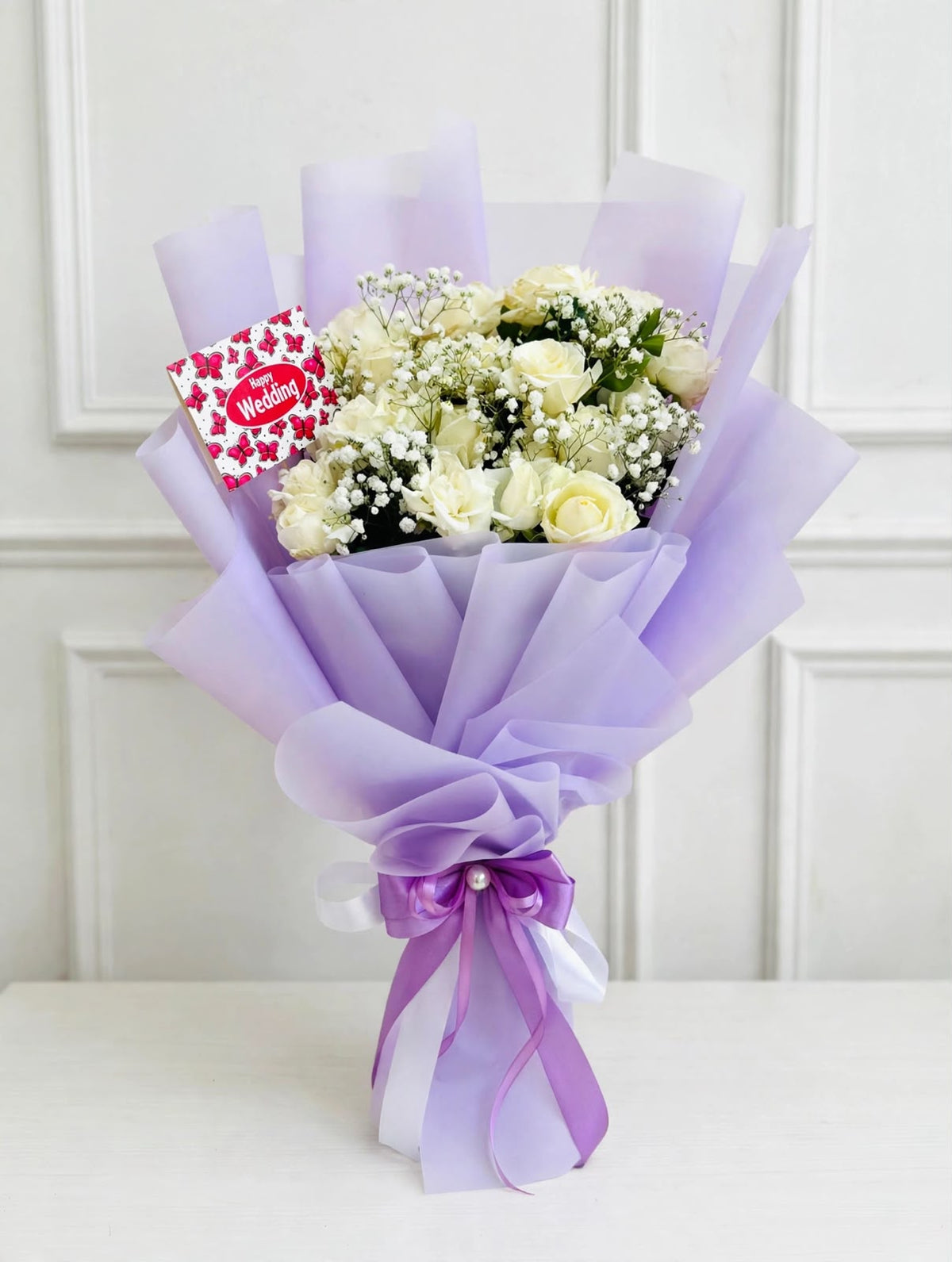 Pure Elegance Bouquet with white roses, baby's breath, lavender wrapping, and purple ribbon