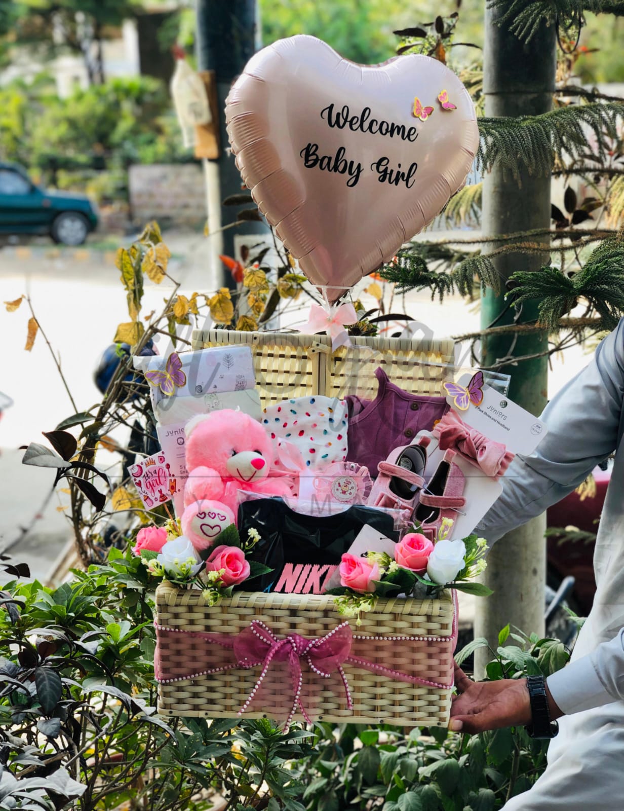 Welcome Baby Girl gift basket with newborn clothing, plush toy, shoes and heart-shaped balloon