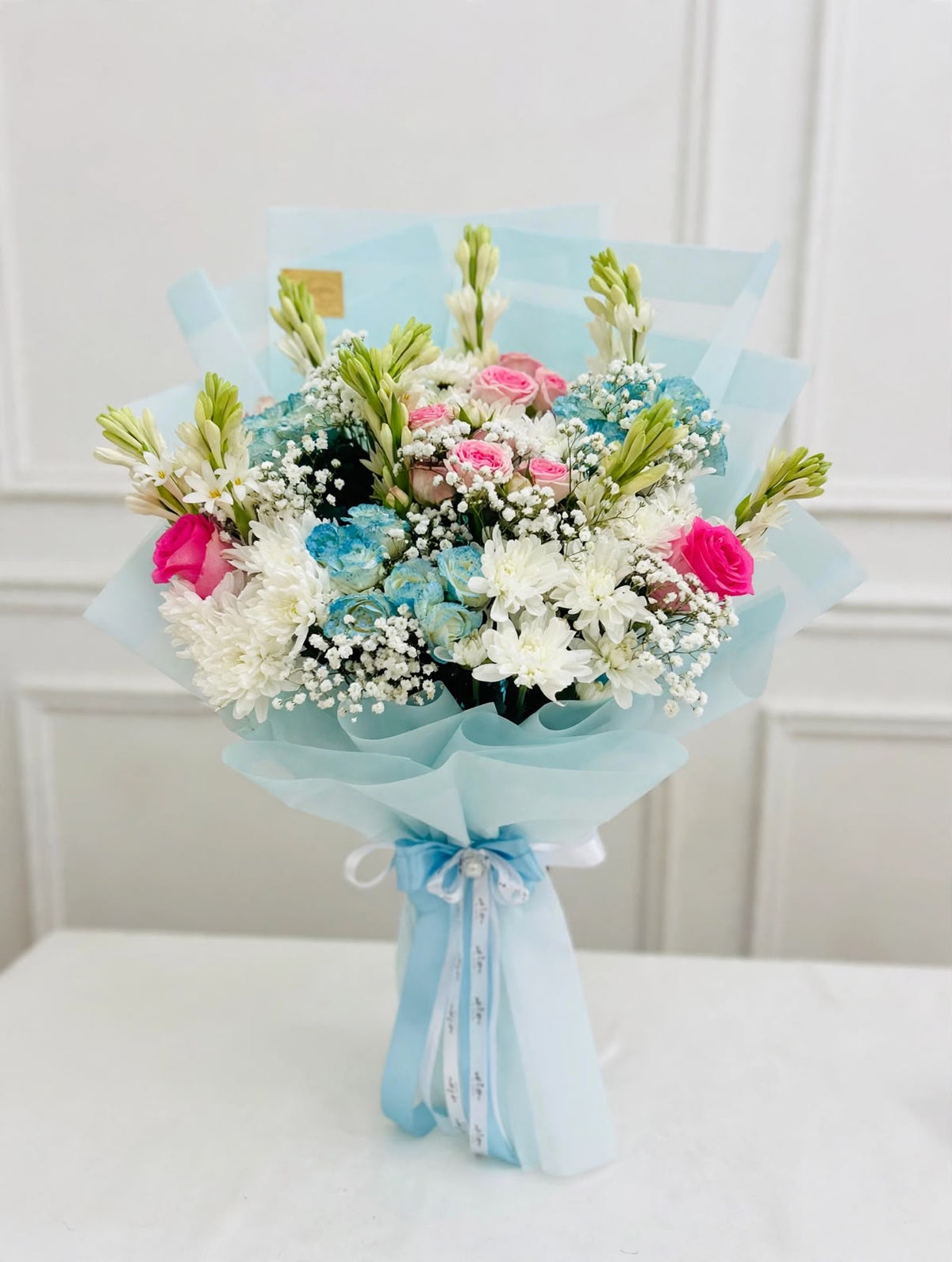Blue birthday gift set featuring a floral cake, mixed flower bouquet in blue wrapping, and blue silver confetti balloons

