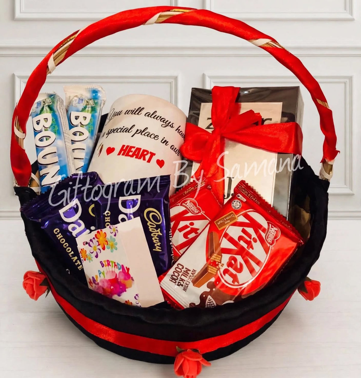 Heartfelt Chocolate Mug Basket with printed mug, Cadbury Dairy Milk, KitKat, Bounty and a Happy Birthday card in a black and red basket with roses