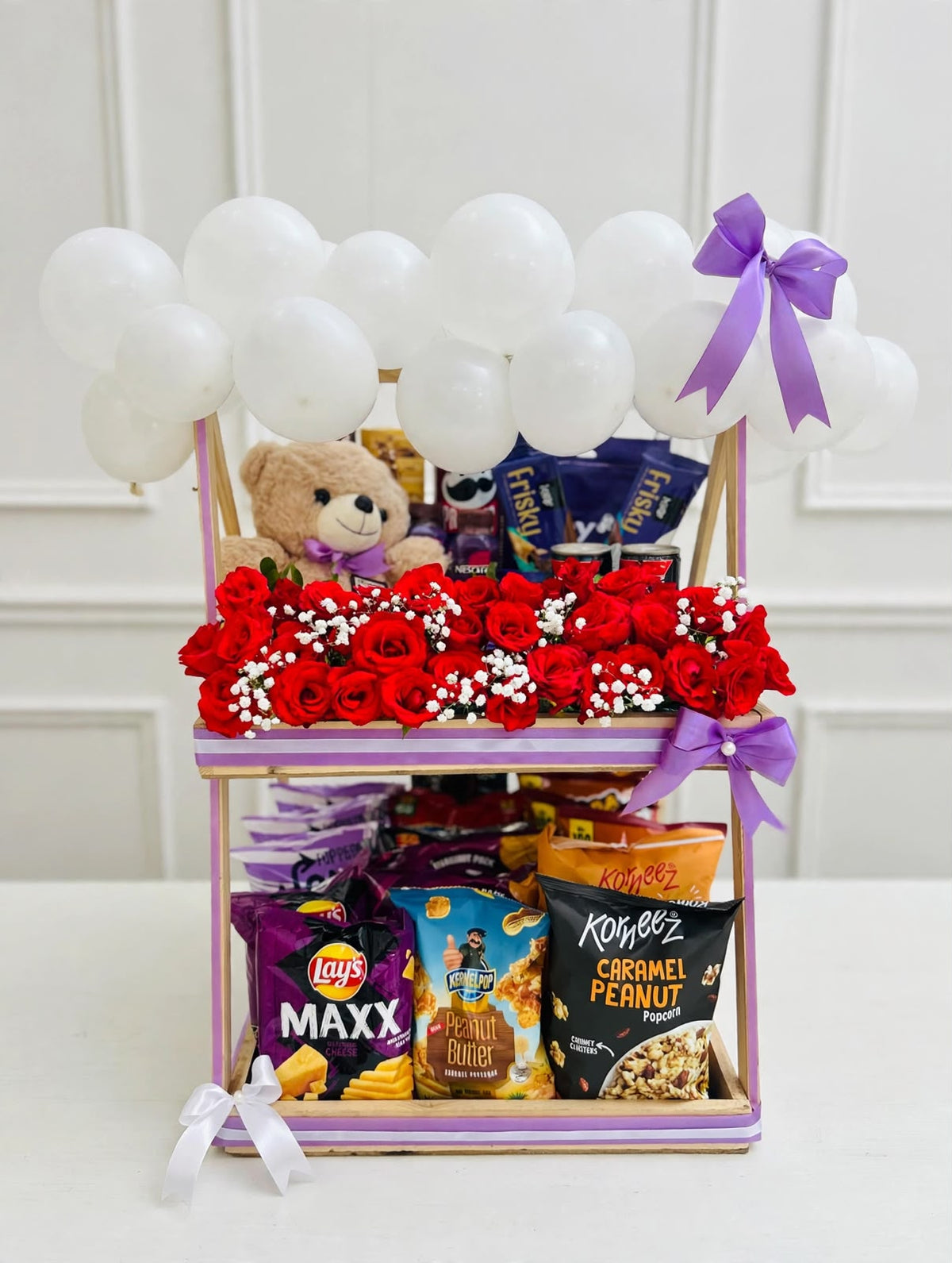 Royal Snack Surprise two-tier gift stand with red roses, teddy bear, assorted snacks, and white balloons